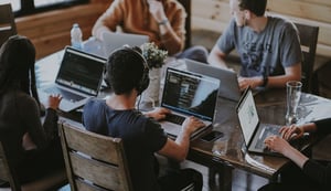 Man on computer at table with other workers